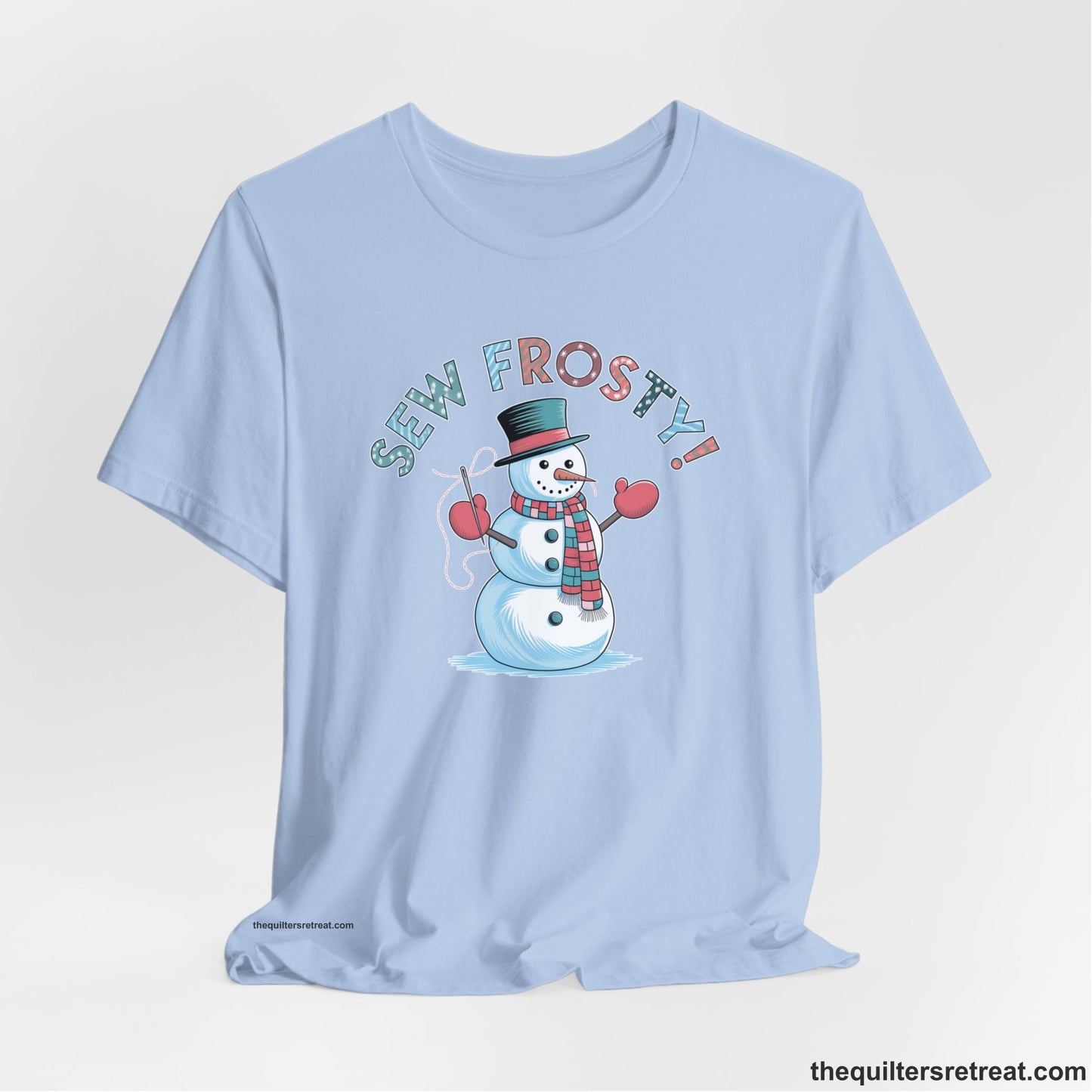 A Baby Blue Short Sleeve T-Shirt with a playful snowman sewing illustration with "Sew Frosty!" text in a festive style