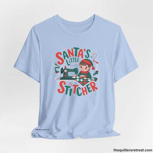 A Baby Blue Short Sleeve T-Shirt with a santa's little stitcher elf sewing quilt with festive colors in playful style