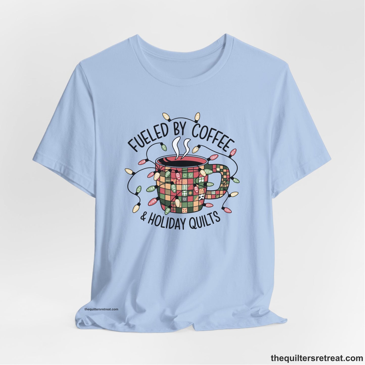 A Baby Blue Short Sleeve T-Shirt with a patchwork coffee mug with colorful lights and subtle "Fueled by Coffee" text in festive style
