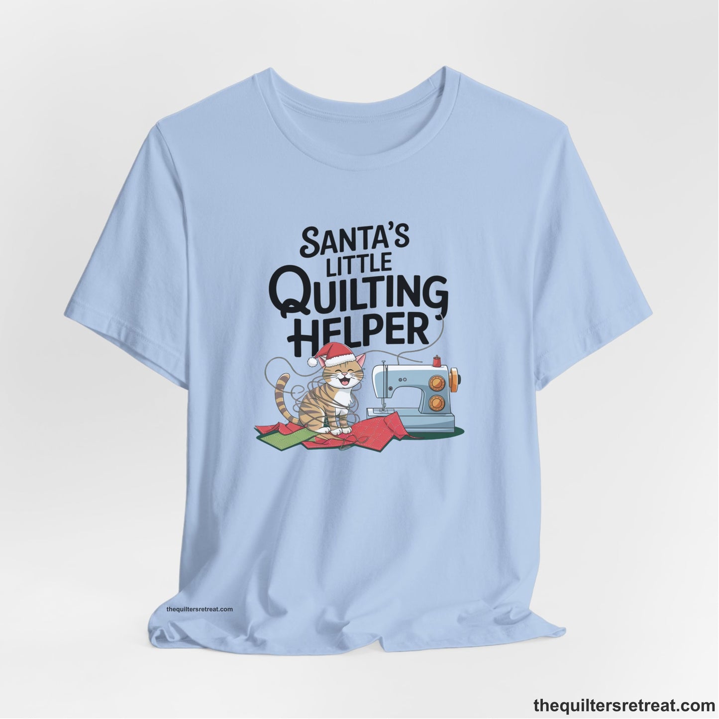 A Baby Blue Short Sleeve T-Shirt with a santa-hat-wearing kitten with a sewing machine and "Santa's Little Quilting Helper" text in playful style