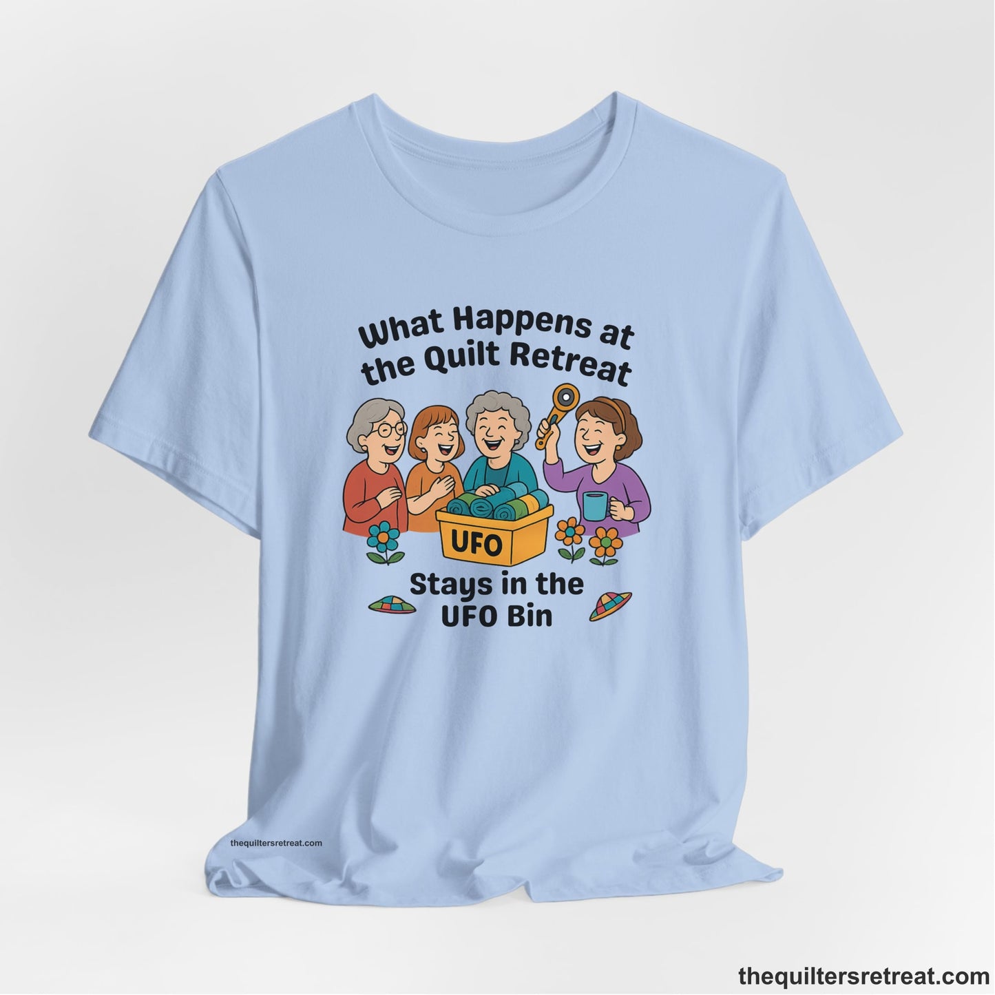 A Baby Blue Short Sleeve T-Shirt with a four smiling women with unfinished fabric objects and playful "UFO" text in a cartoon style