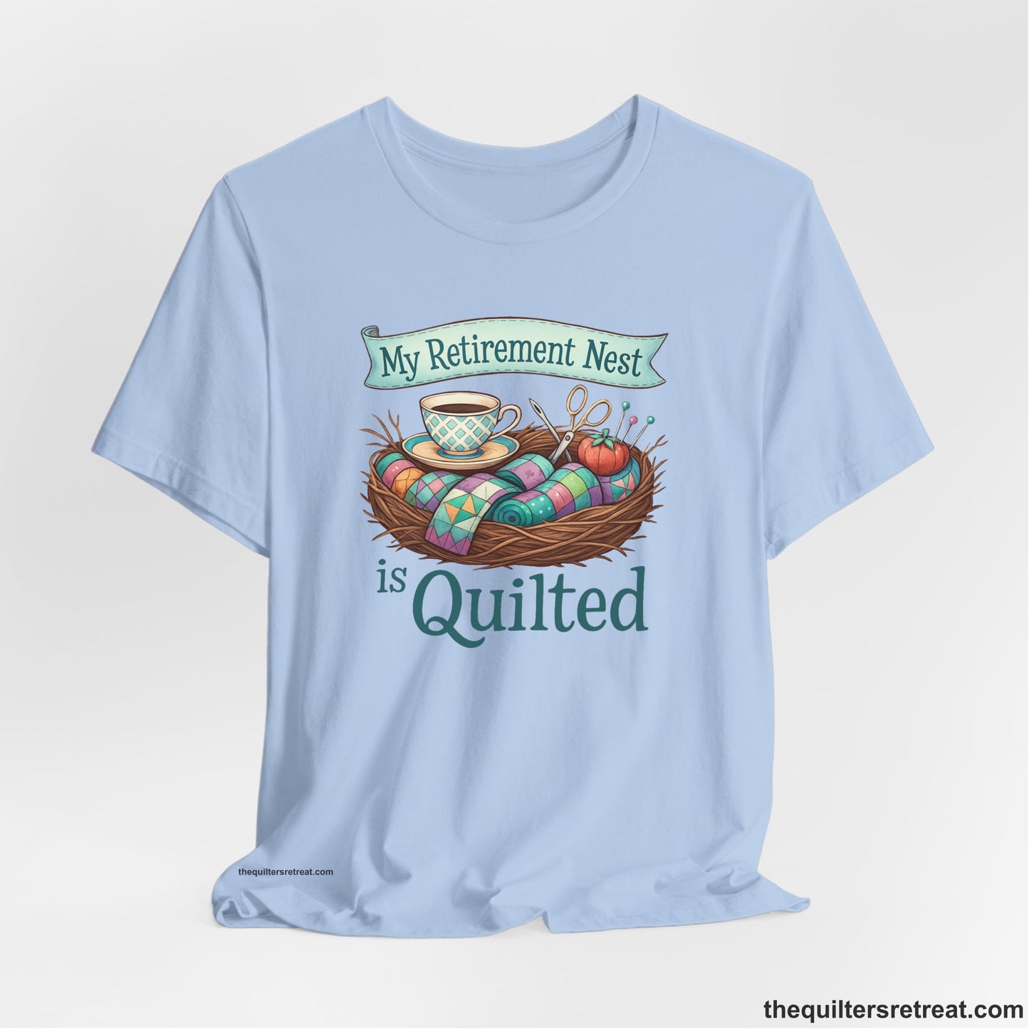 A Baby Blue Short Sleeve T-Shirt with a My Retirement Nest is Quilted text with a cozy sewing elements illustration