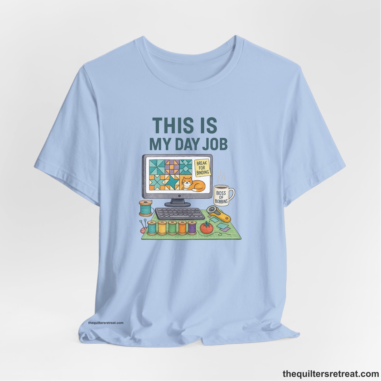 A Baby Blue Short Sleeve T-Shirt with a computer quilt design, cat illustration, "THIS IS MY DAY JOB" text with sewing tools, playful style