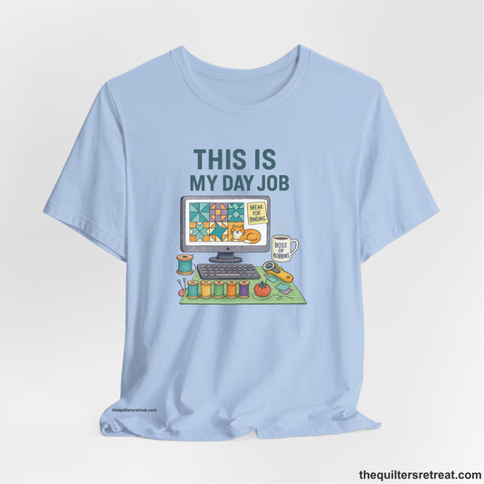 A Baby Blue Short Sleeve T-Shirt with a computer quilt design, cat illustration, "THIS IS MY DAY JOB" text with sewing tools, playful style