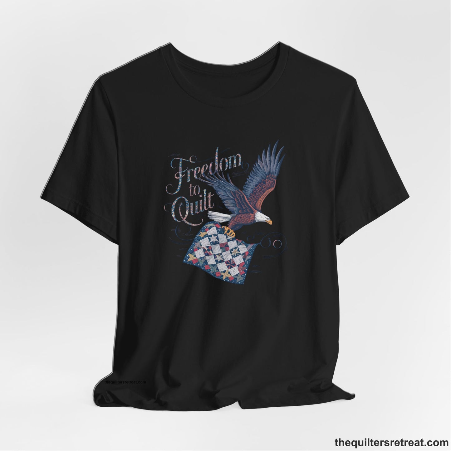 A Black Short Sleeve T-Shirt with a freedom to quilt text with an eagle carrying a colorful patchwork quilt in vintage style