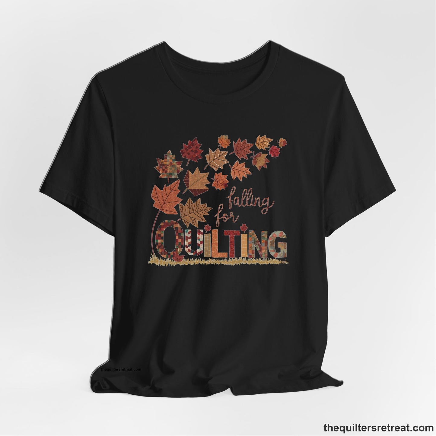 A Black Short Sleeve T-Shirt with a falling autumn leaves and "Falling for Quilting" text in a patchwork style
