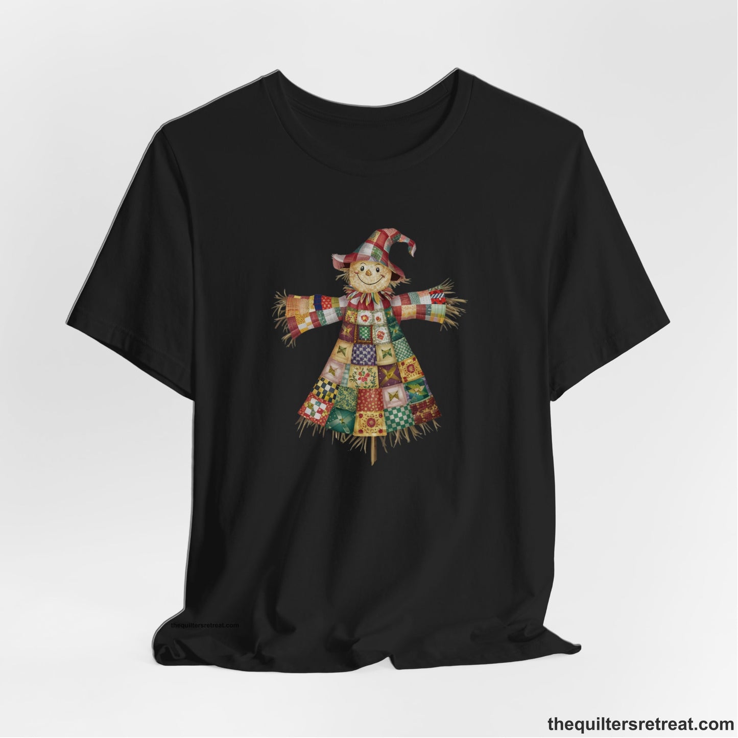 A Black Short Sleeve T-Shirt with a patchwork scarecrow with a cheerful face in a whimsical style