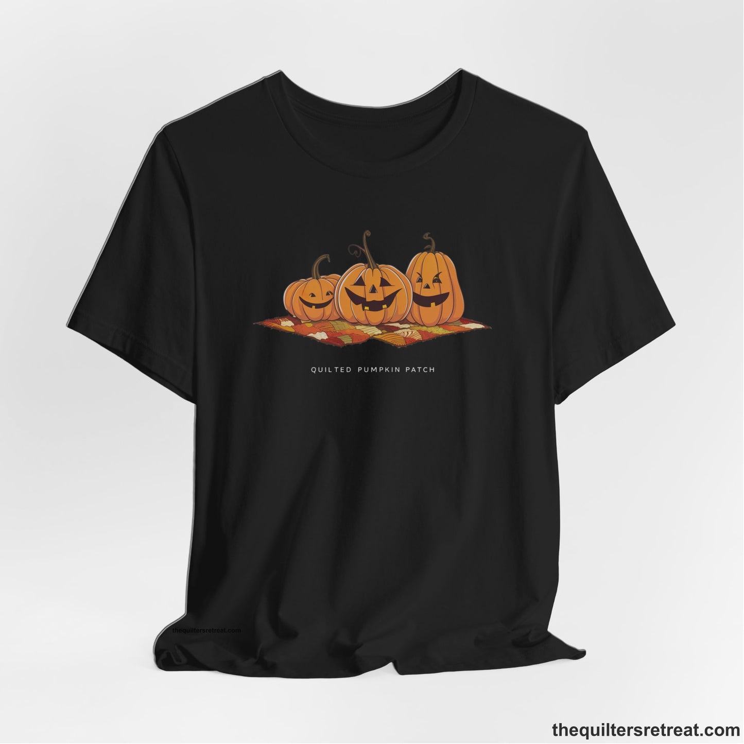 A Black Short Sleeve T-Shirt with a playful jack-o'-lantern trio on a quilt with "Quilted Pumpkin Patch" text