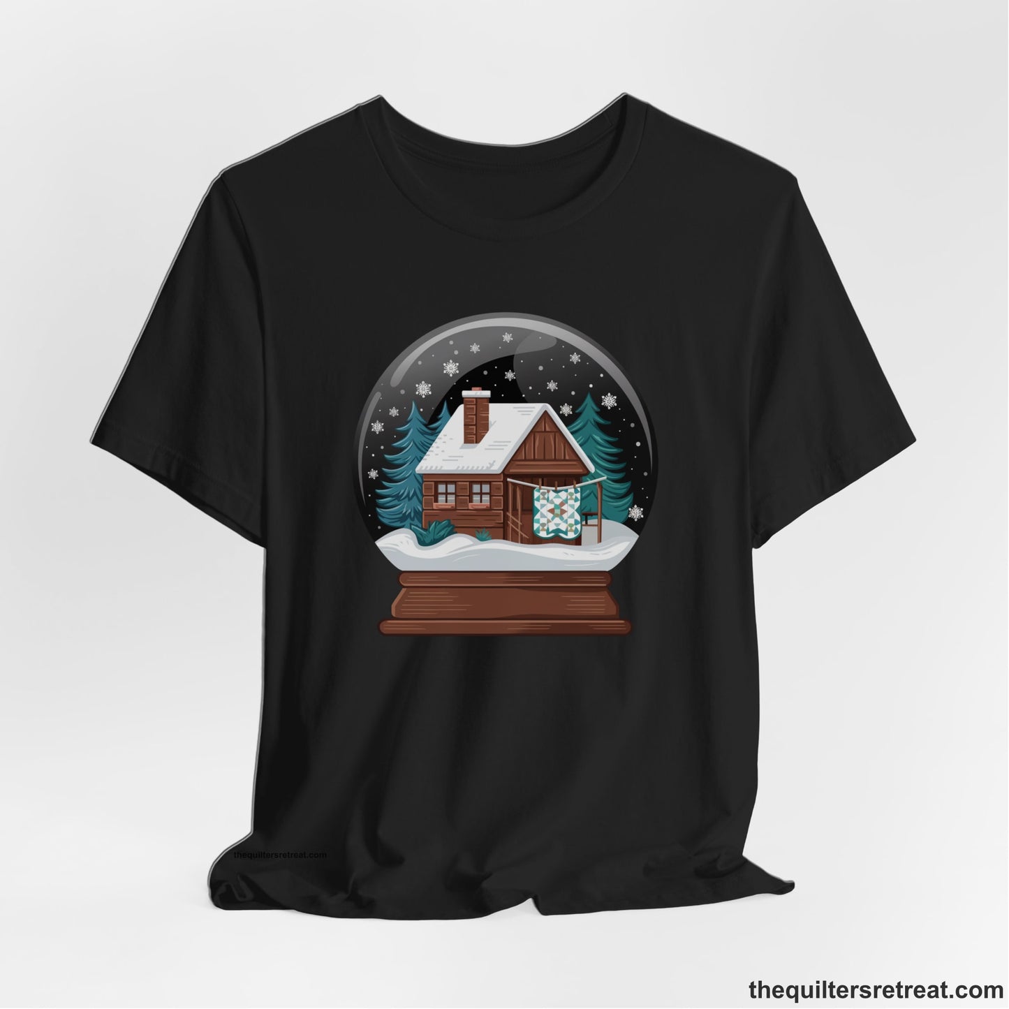 A Black Short Sleeve T-Shirt with a cabin in a snow globe with snowflakes and trees, in a cozy rustic style