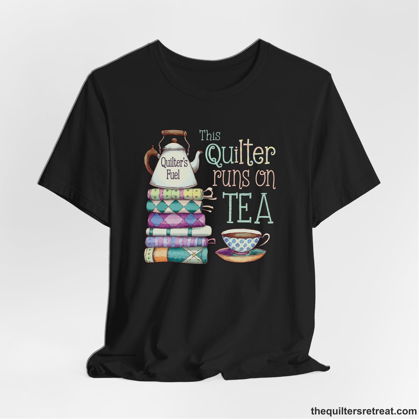A Black Short Sleeve T-Shirt with a stack of colorful quilts with teapot and cup, whimsical "This Quilter Runs on Tea" text