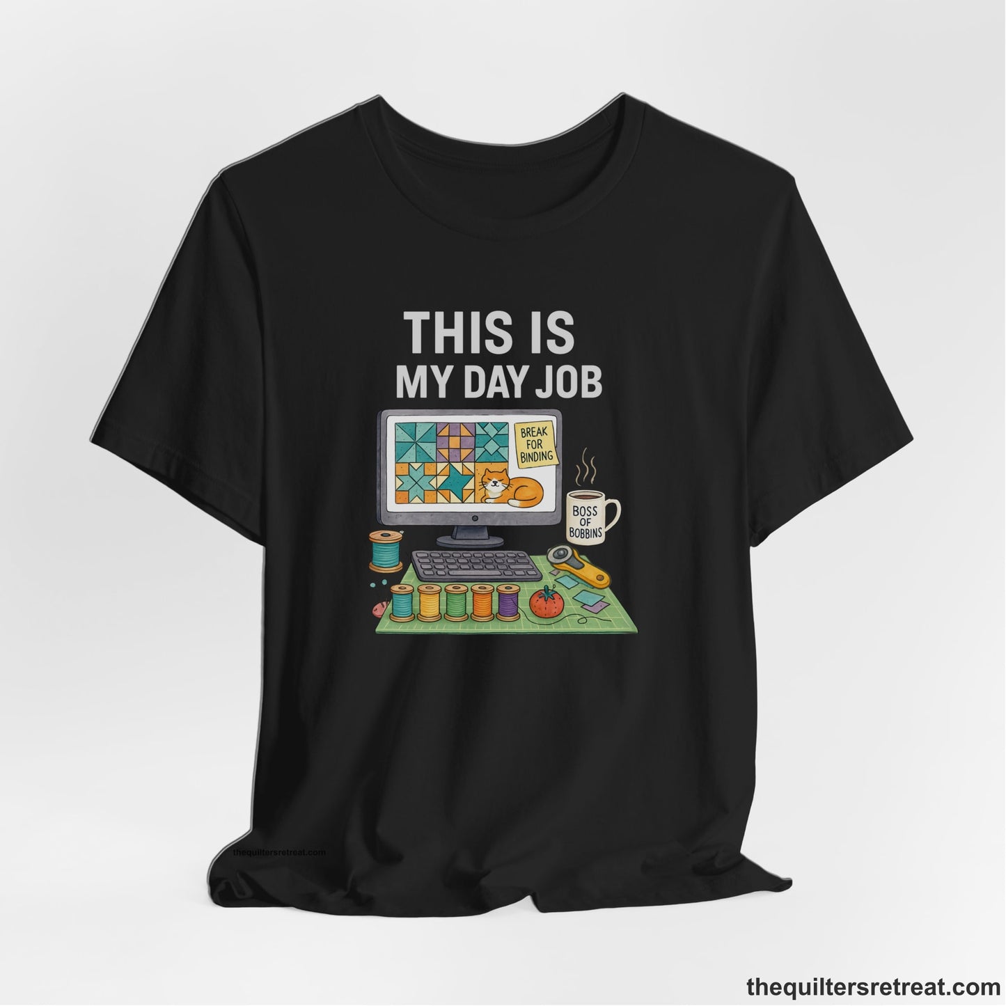 A Black Short Sleeve T-Shirt with a computer quilt design, cat illustration, "THIS IS MY DAY JOB" text with sewing tools, playful style