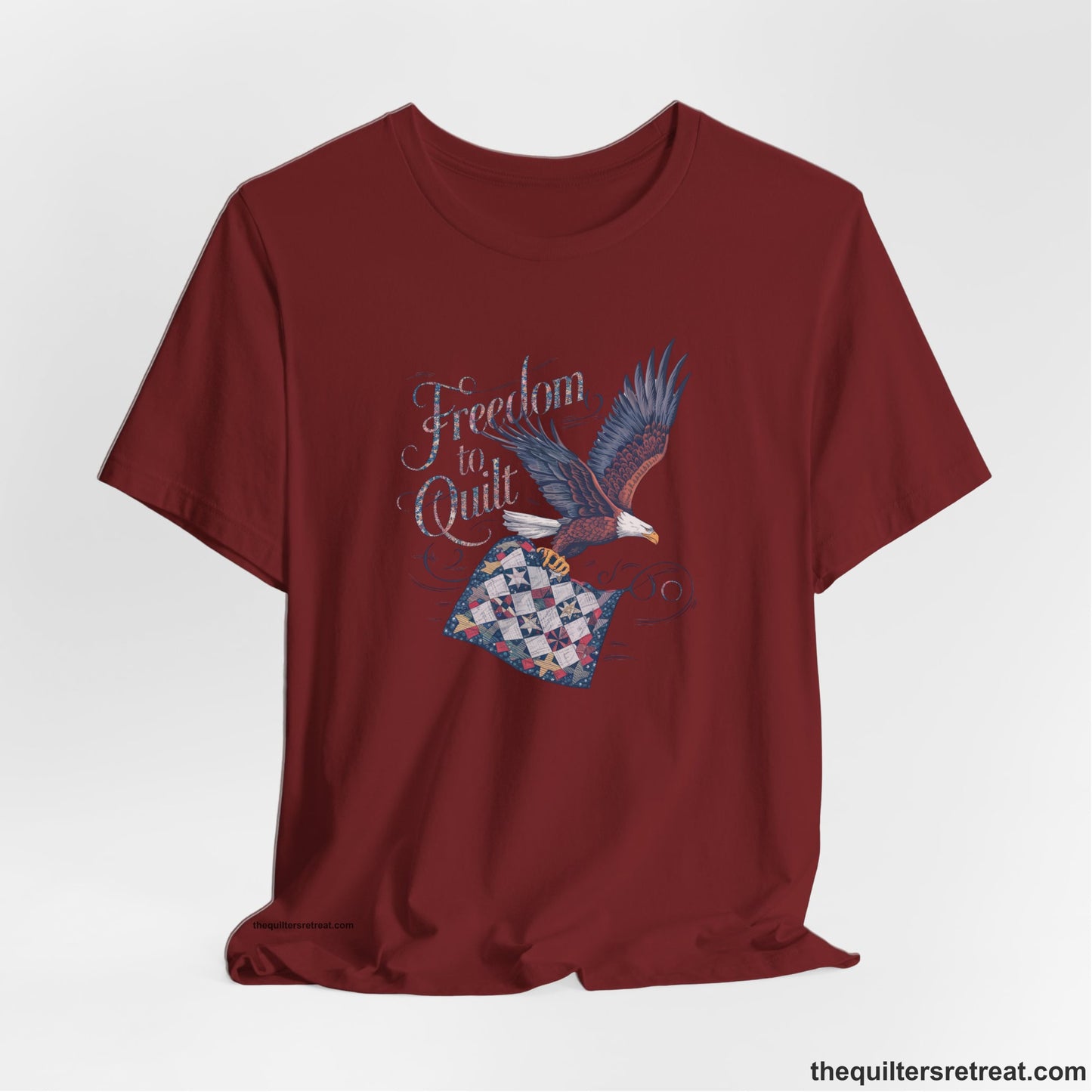 A Short Sleeve T-Shirt with a freedom to quilt text with an eagle carrying a colorful patchwork quilt in vintage style