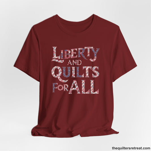 A Cardinal Short Sleeve T-Shirt with a Liberty and Quilts for All" text with patchwork quilt pattern in a vintage style