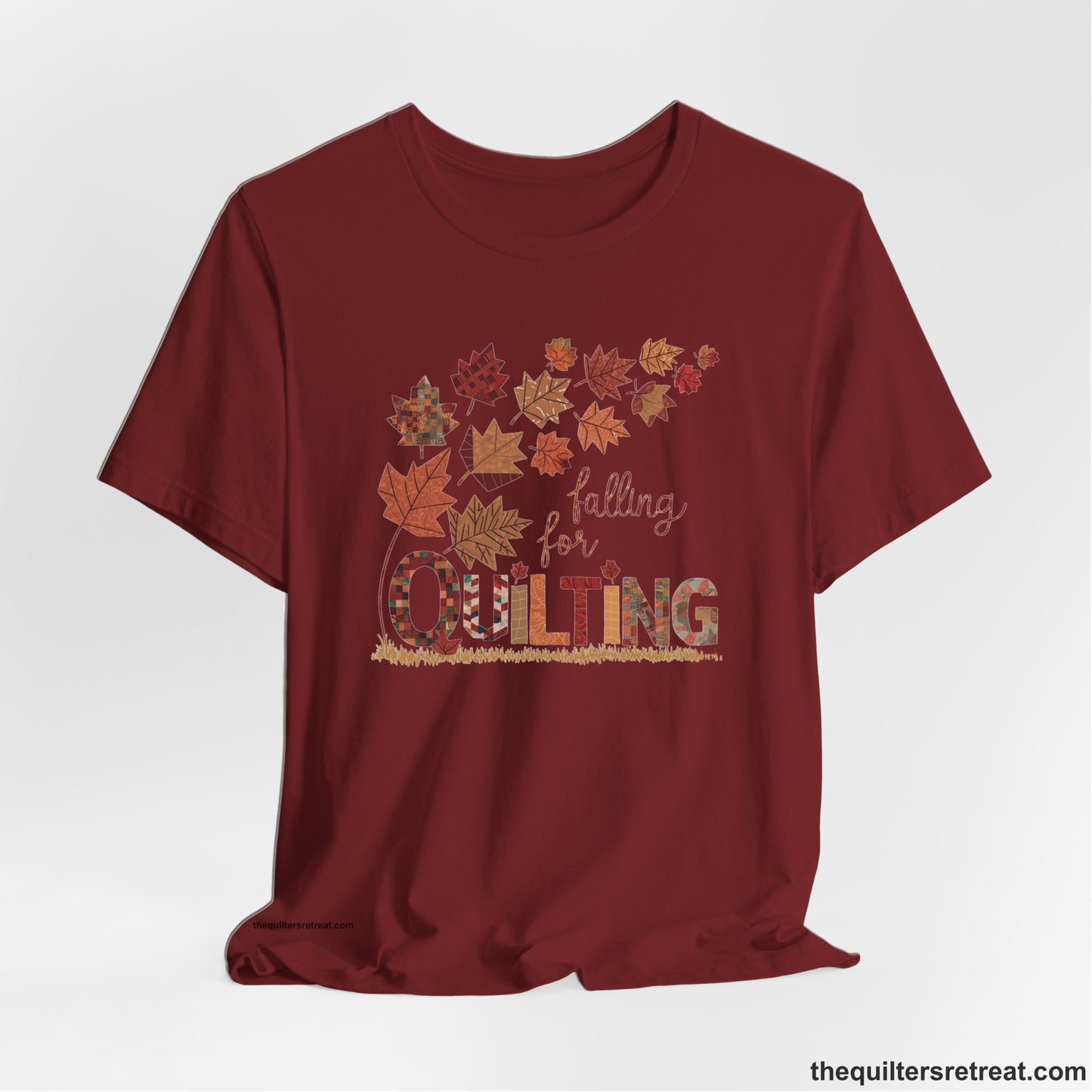 A Cardinal Short Sleeve T-Shirt with a falling autumn leaves and "Falling for Quilting" text in a patchwork style
