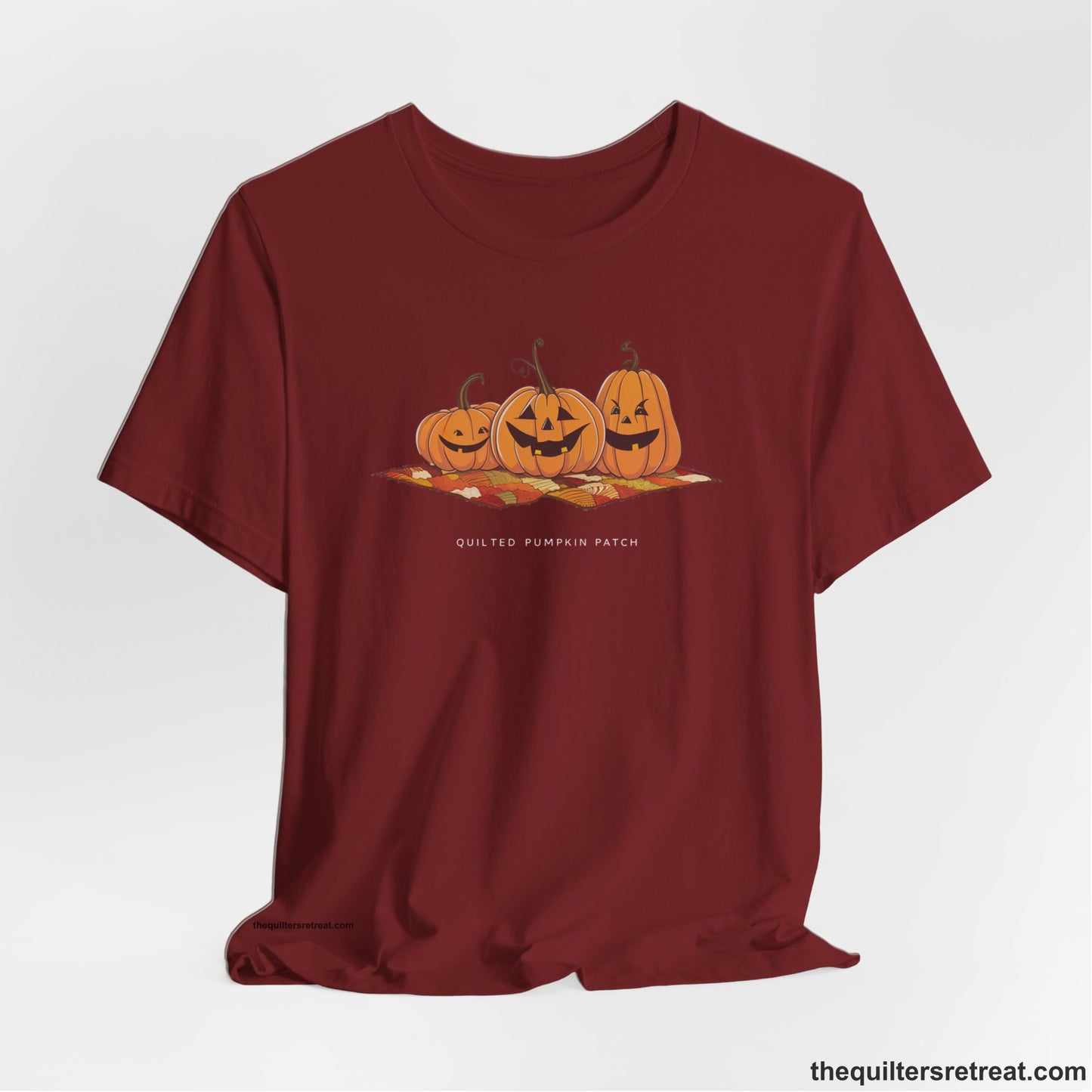 A Cardinal Short Sleeve T-Shirt with a playful jack-o'-lantern trio on a quilt with "Quilted Pumpkin Patch" text
