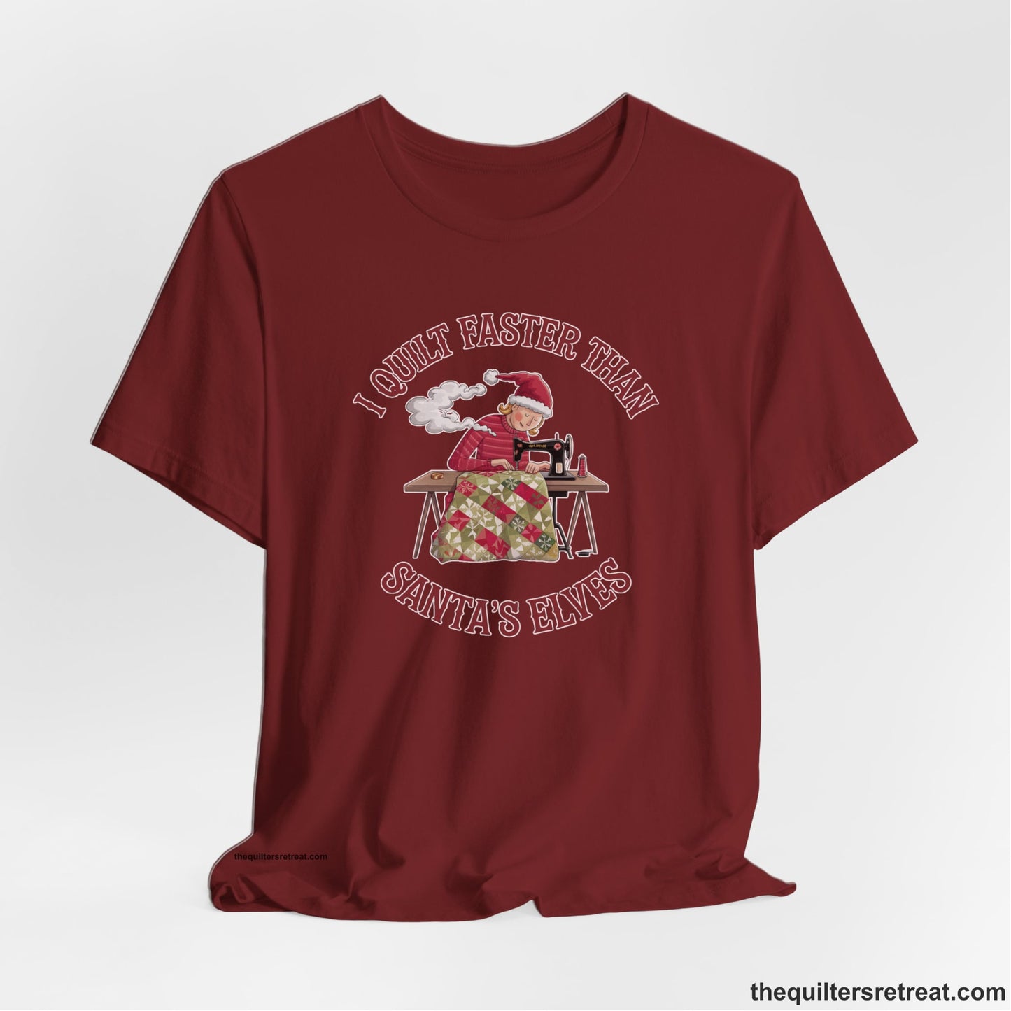 A Cardinal Short Sleeve T-Shirt with a whimsical illustration of a quilting woman with "I Quilt Faster Than Santa's Elves" text