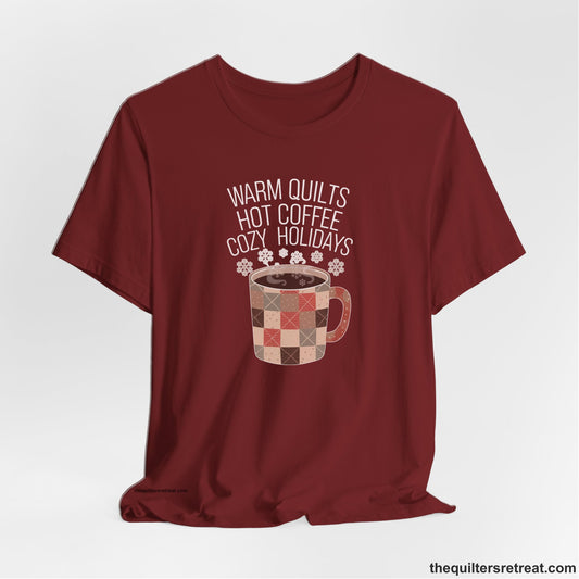 A Cardinal Short Sleeve T-Shirt with a warm quilts hot coffee cozy holidays text with a patchwork mug and snowflakes