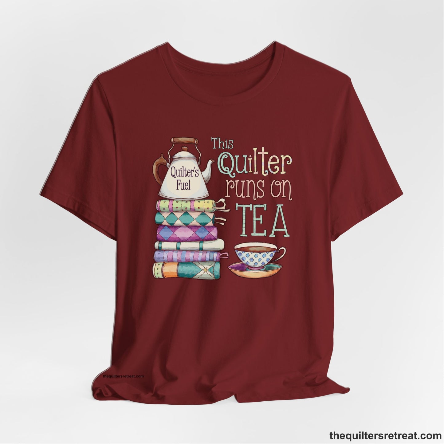 A Cardinal Short Sleeve T-Shirt with a stack of colorful quilts with teapot and cup, whimsical "This Quilter Runs on Tea" text