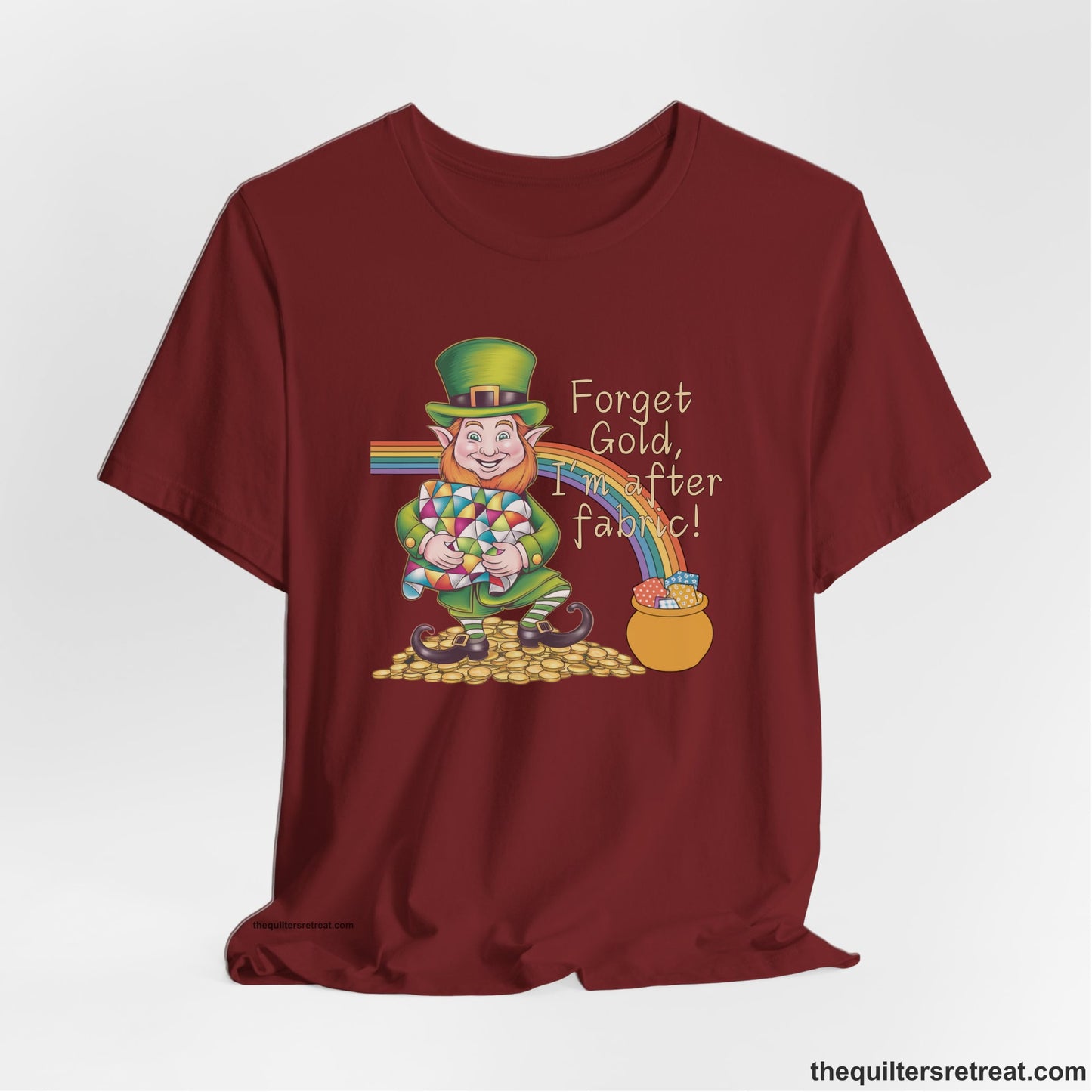 A Cardinal Short Sleeve T-Shirt with a leprechaun with colorful quilt and rainbow, whimsical "Forget Gold, I'm after fabric!" text