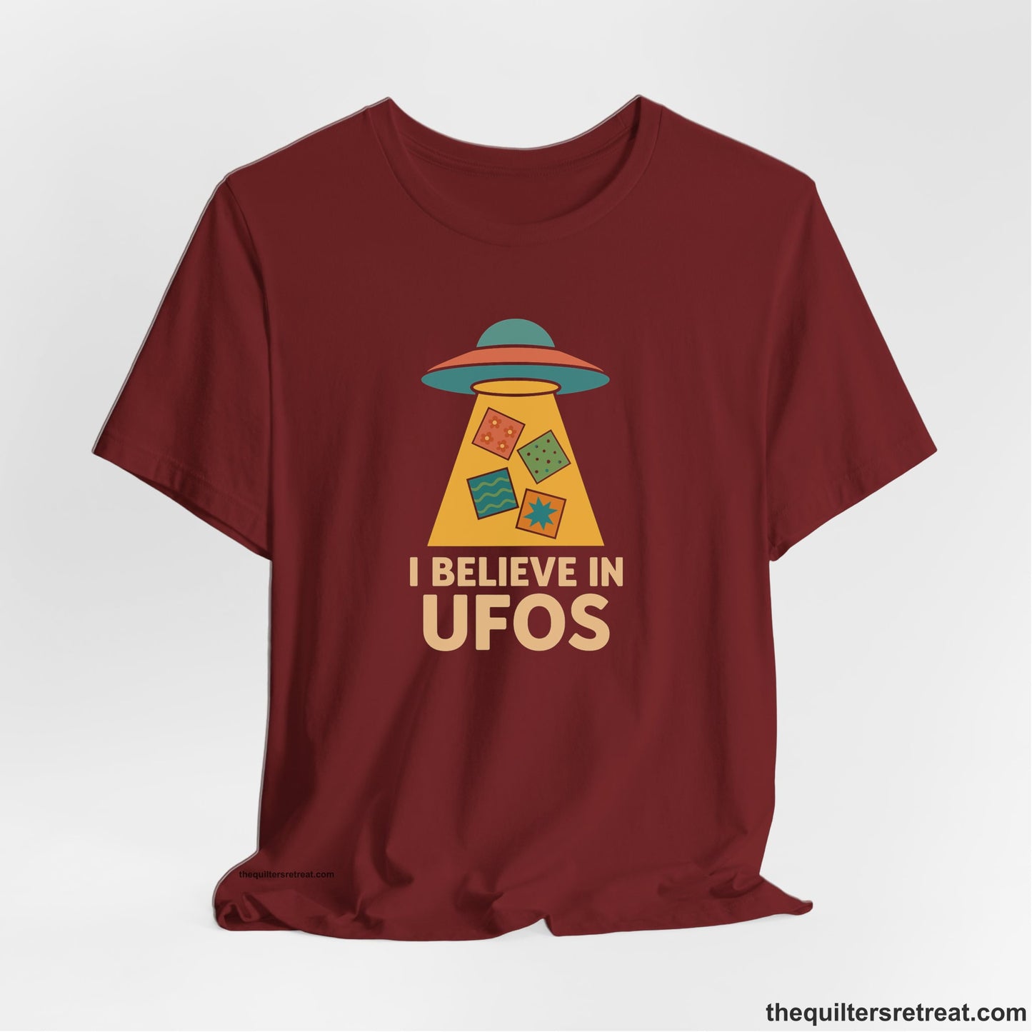 A Cardinal Short Sleeve T-Shirt with a colorful UFO with quilt patterns and bold "I Believe in UFOs" text in retro style
