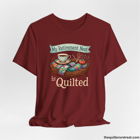 A Short Sleeve T-Shirt with a My Retirement Nest is Quilted text with a cozy sewing elements illustration