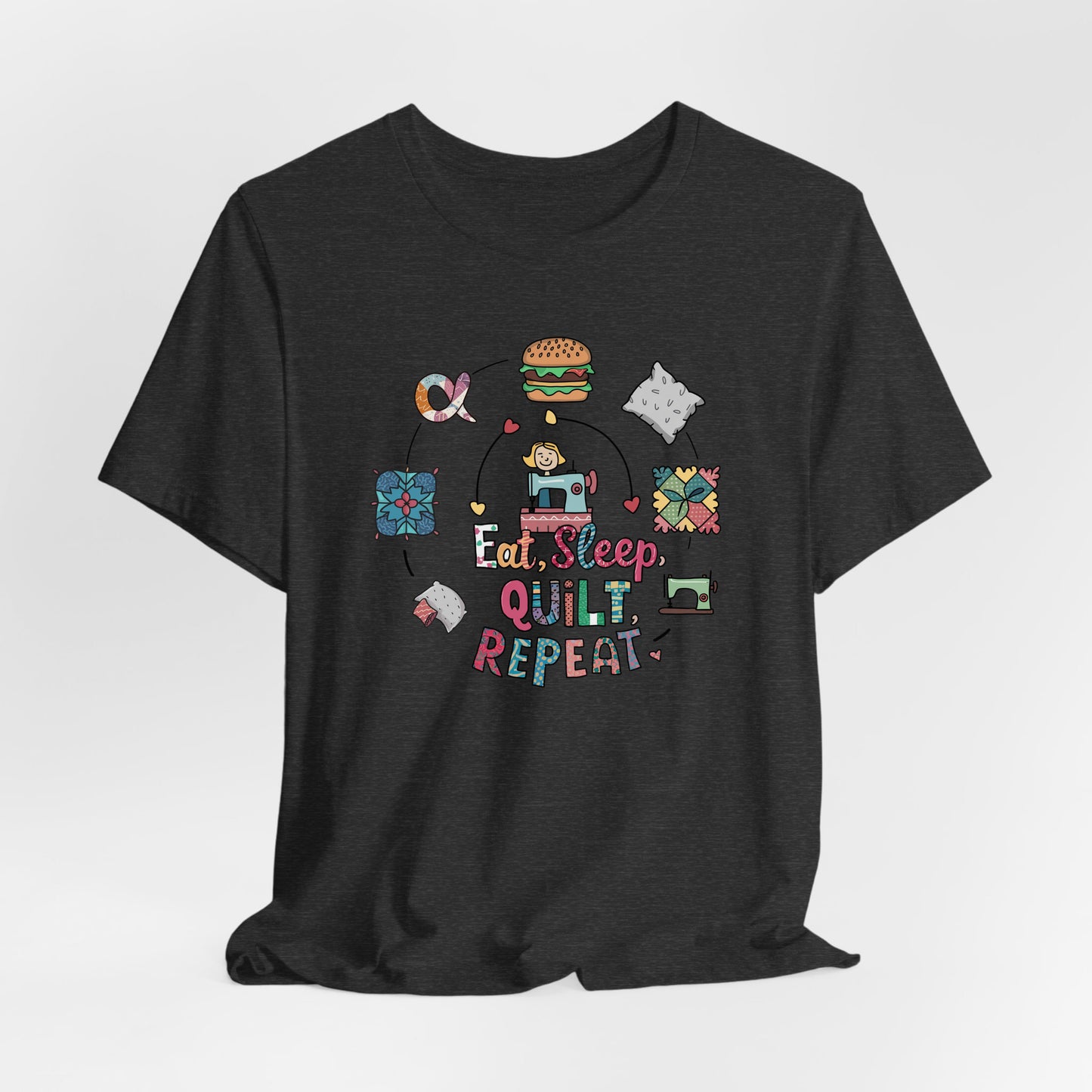 A Dark Grey Heather Short Sleeve T-Shirt with a cute quilting elements with "Eat, Sleep, Quilt, Repeat" text in playful style