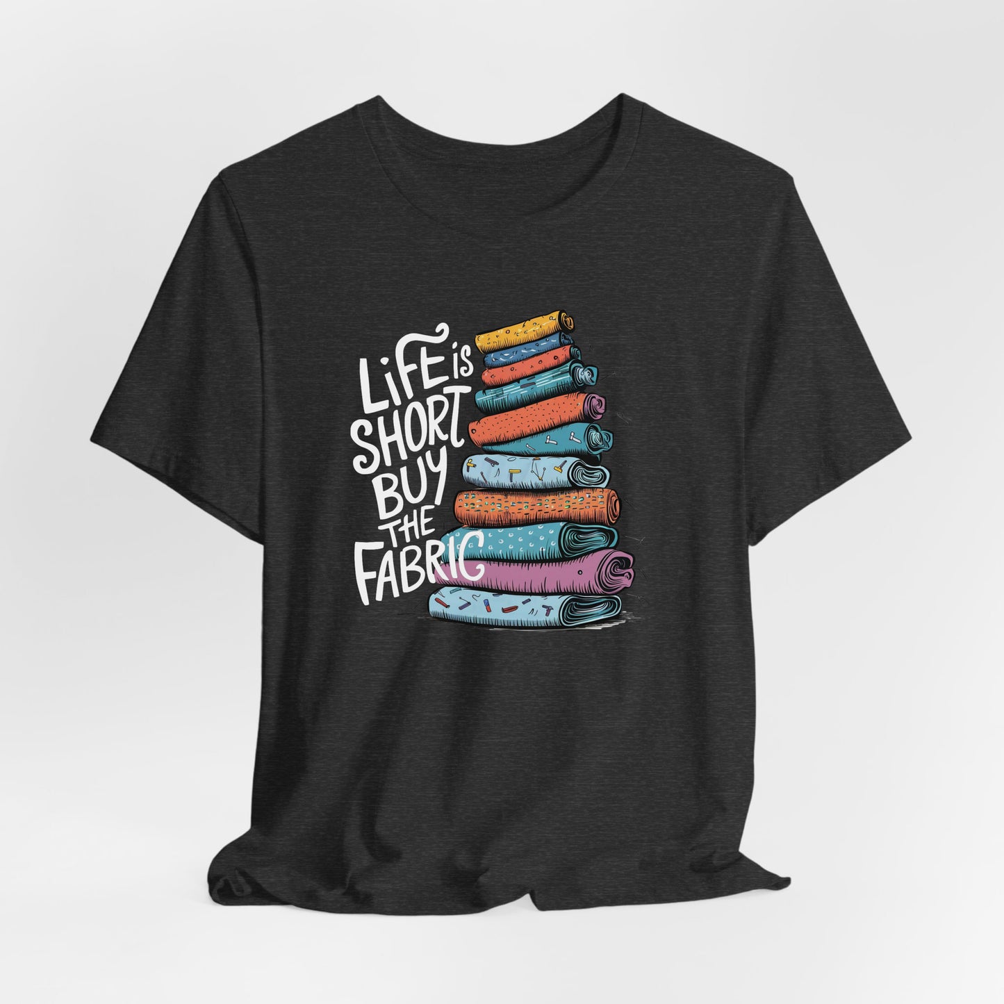 A Dark Grey Heather Short Sleeve T-Shirt with a illustration of colorful fabric rolls with bold "Life is Short Buy the Fabric" text