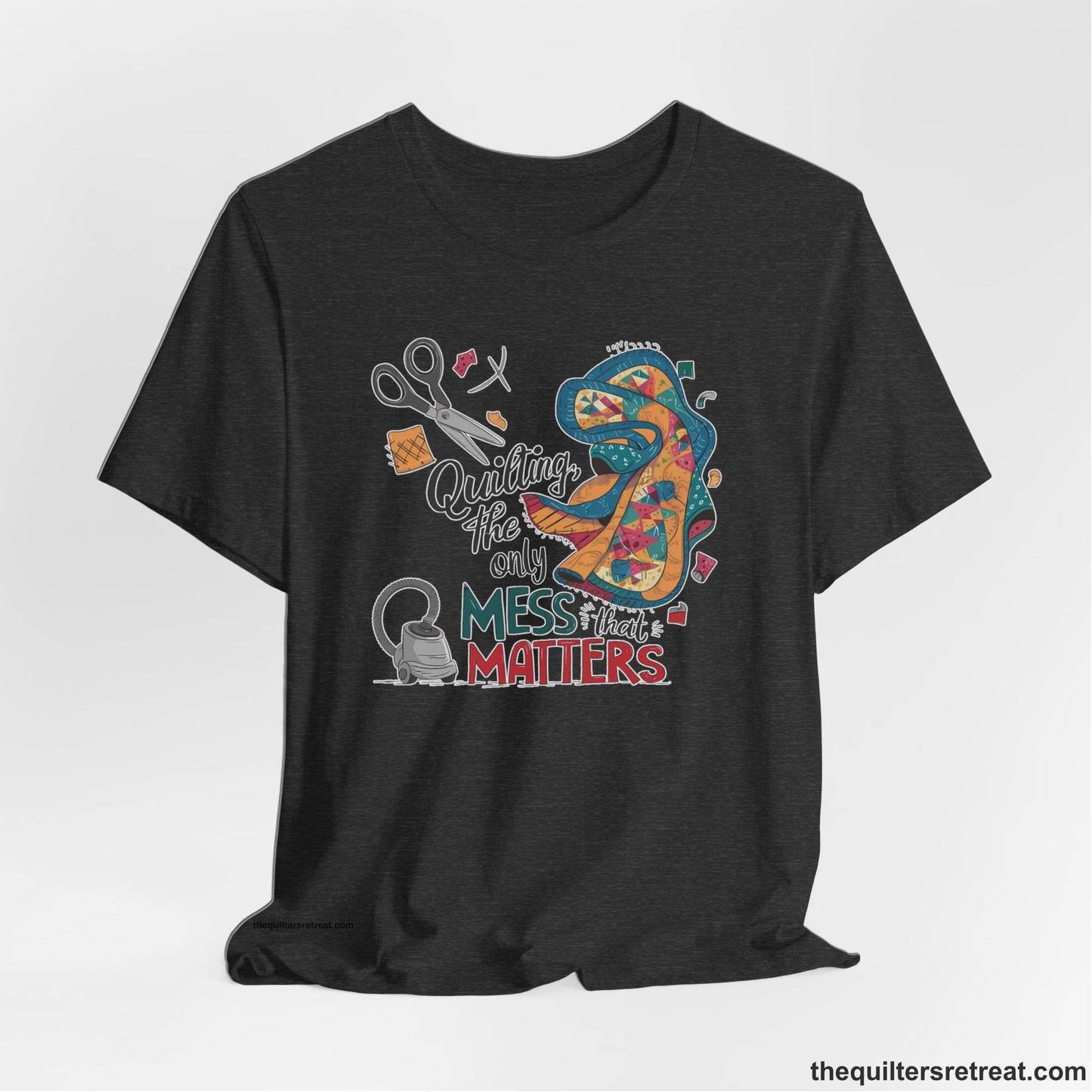 A Dark Grey Heather Short Sleeve T-Shirt with a quilting tools and patchwork pieces with bold "Quilting, the only mess that matters" text