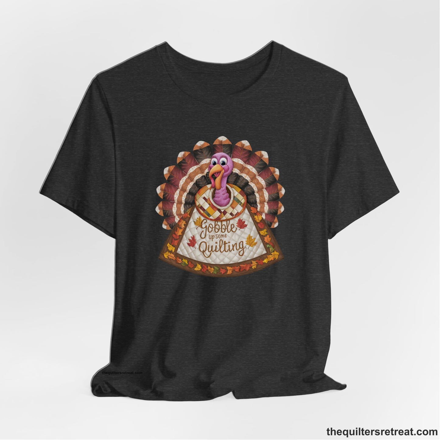 A Dark Grey Heather Short Sleeve T-Shirt with a colorful turkey with quilted feathers and "Gobble Up Some Quilting" text in a playful style