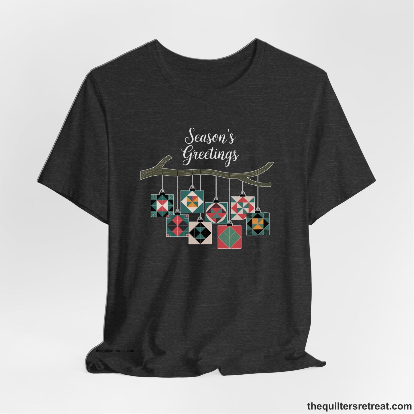 A Dark Grey Heather Short Sleeve T-Shirt with a season's greetings text above colorful quilt block ornaments on tree branch in rustic style