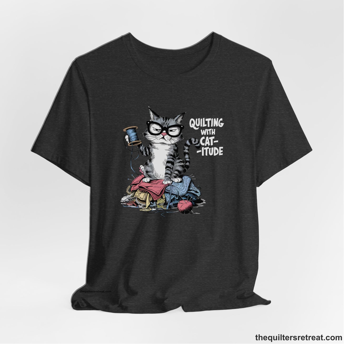 A Dark Grey Heather Short Sleeve T-Shirt with a grumpy cat holding thread spool atop fabric pile with "Quilting with Cat-itude" text