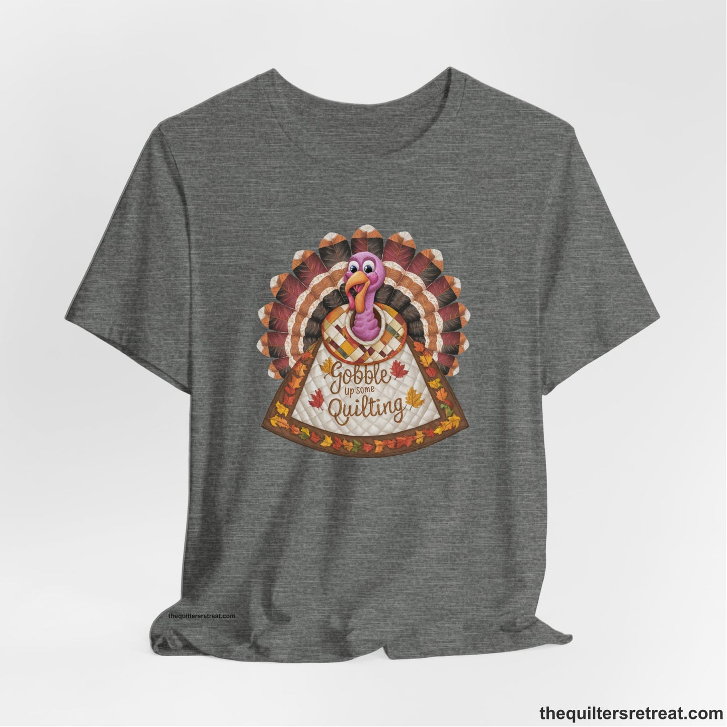 A Deep Heather Short Sleeve T-Shirt with a colorful turkey with quilted feathers and "Gobble Up Some Quilting" text in a playful style