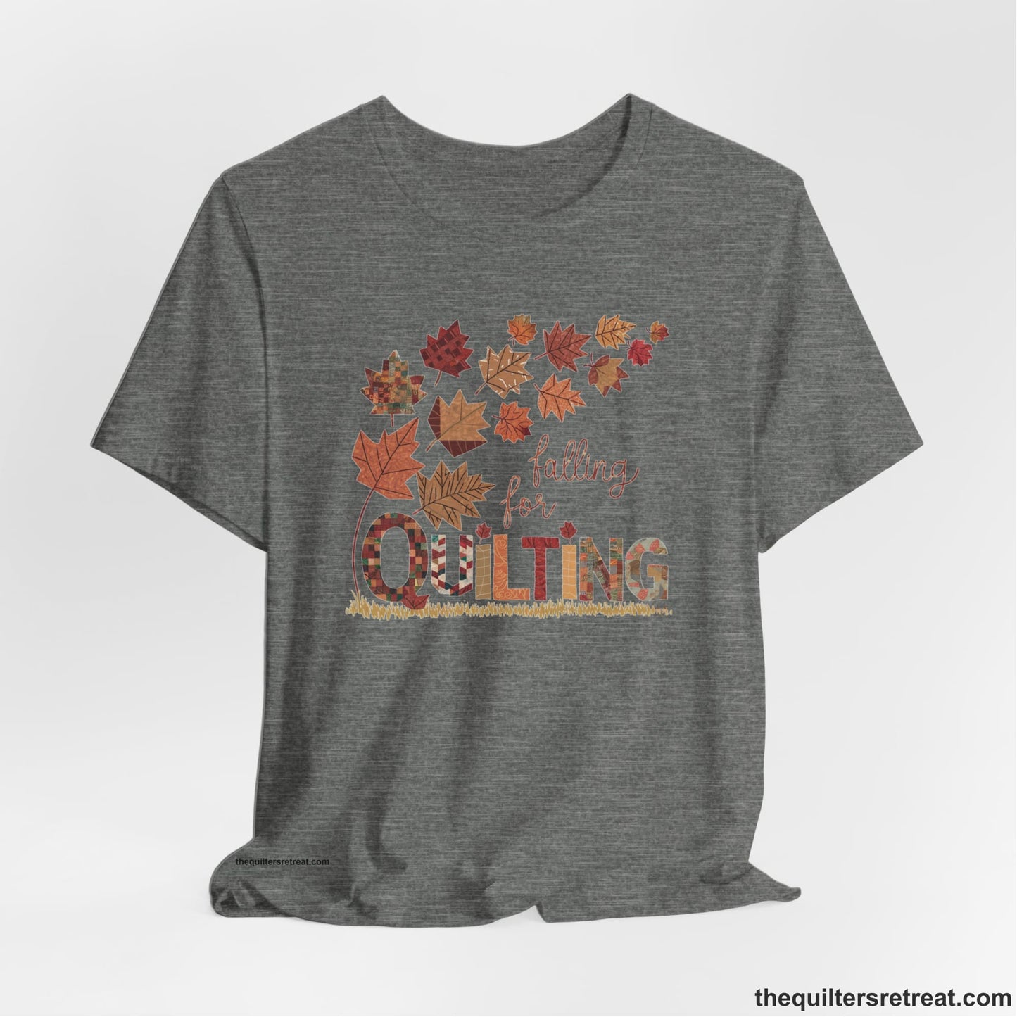 A Deep Heather Short Sleeve T-Shirt with a falling autumn leaves and "Falling for Quilting" text in a patchwork style