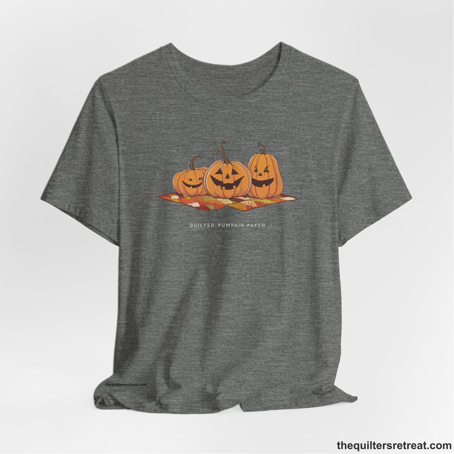A Deep Heather Short Sleeve T-Shirt with a playful jack-o'-lantern trio on a quilt with "Quilted Pumpkin Patch" text