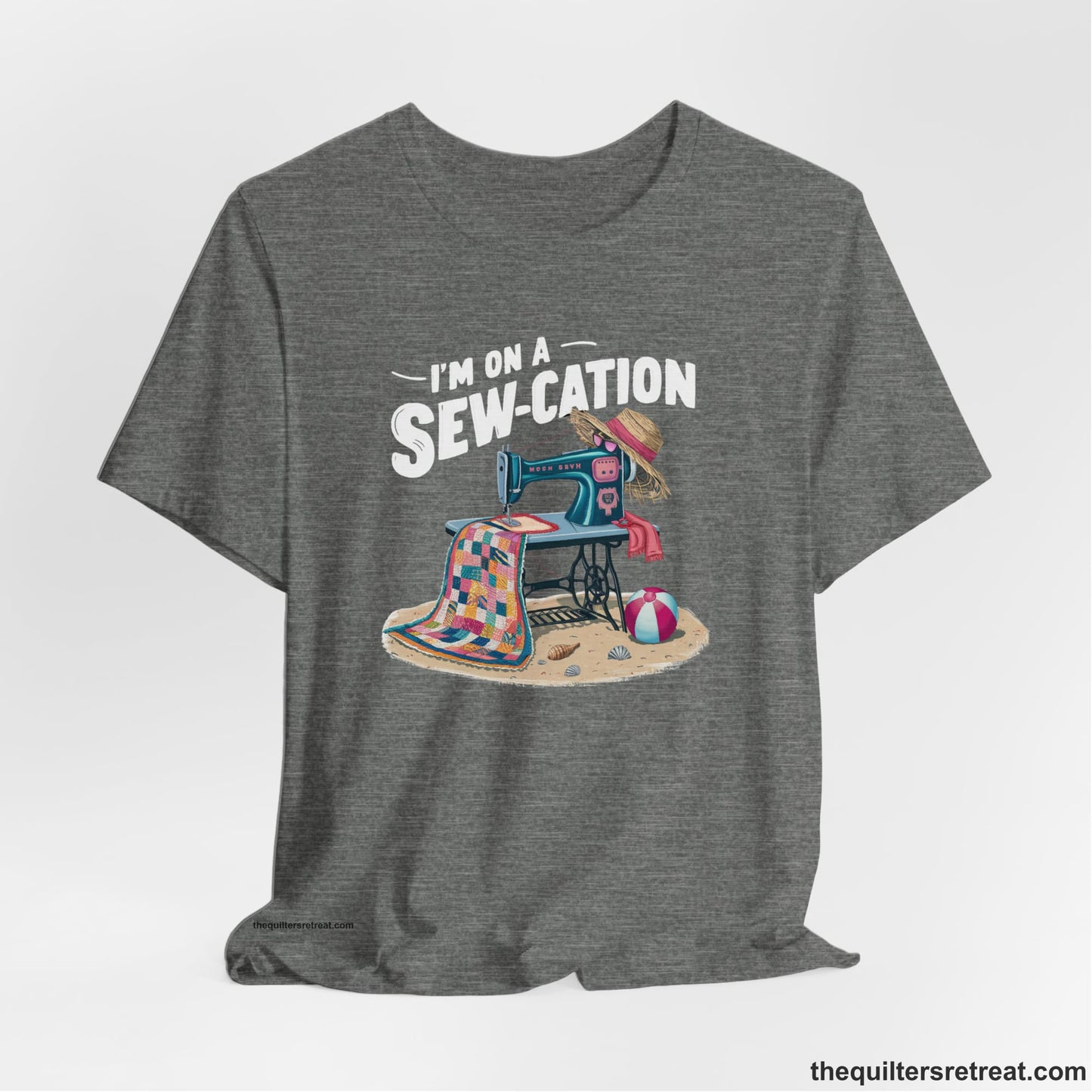 A Deep Heather Short Sleeve T-Shirt with a vintage sewing machine with colorful quilt, beach items, and "I'm On A Sew-Cation" text