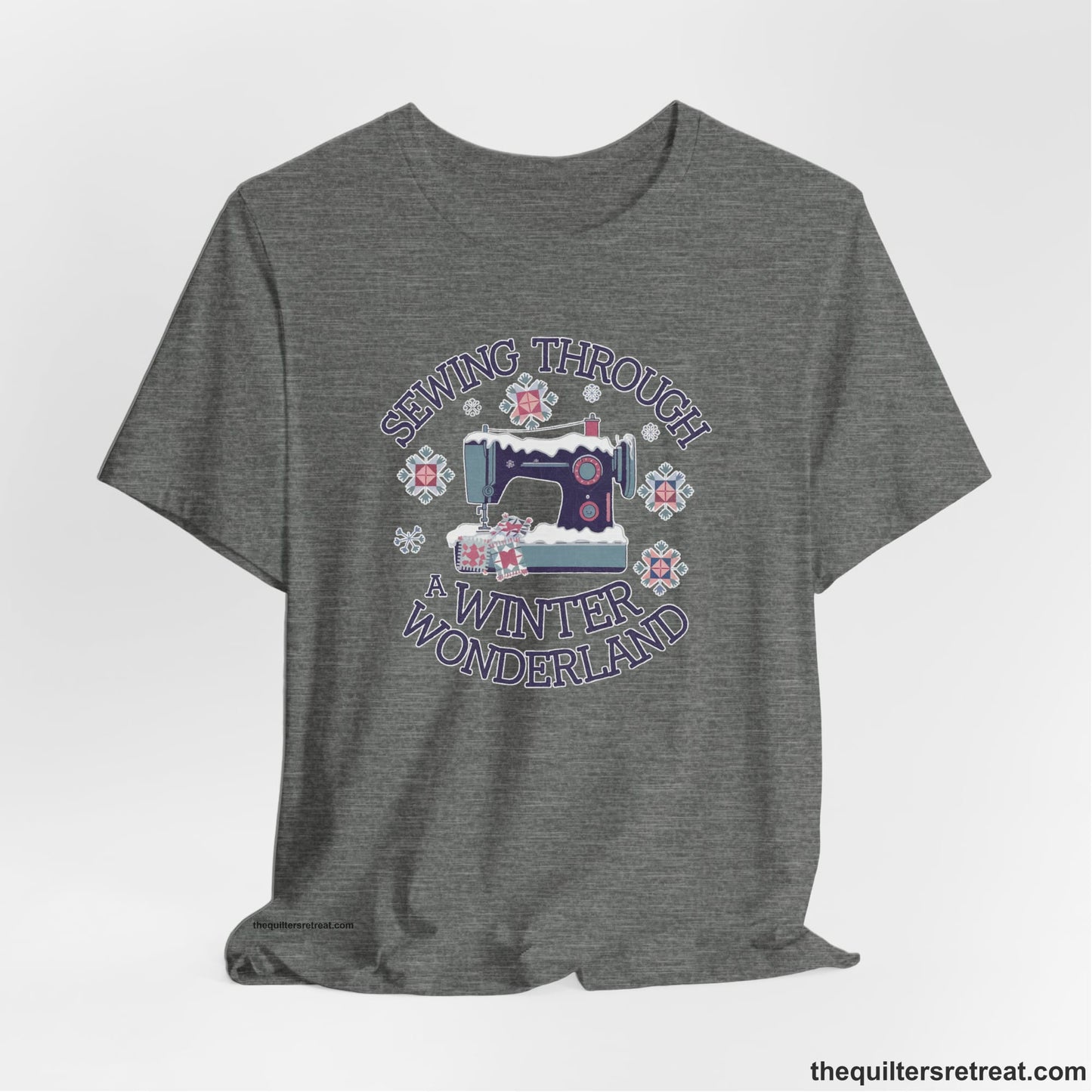 A Deep Heather Short Sleeve T-Shirt with a sewing machine covered in snow with festive quilting elements and "Sewing Through a Winter Wonderland" text