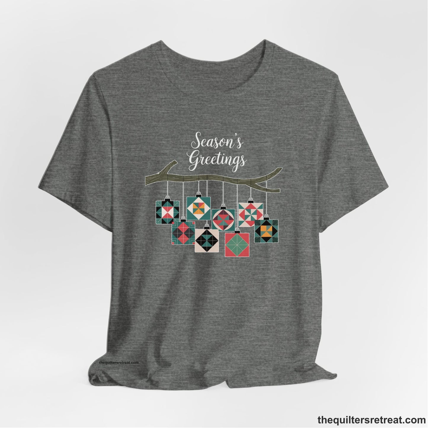 A Deep Heather Short Sleeve T-Shirt with a season's greetings text above colorful quilt block ornaments on tree branch in rustic style