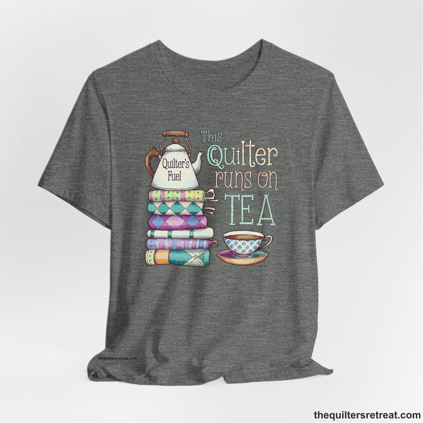 A Deep Heather Short Sleeve T-Shirt with a stack of colorful quilts with teapot and cup, whimsical "This Quilter Runs on Tea" text