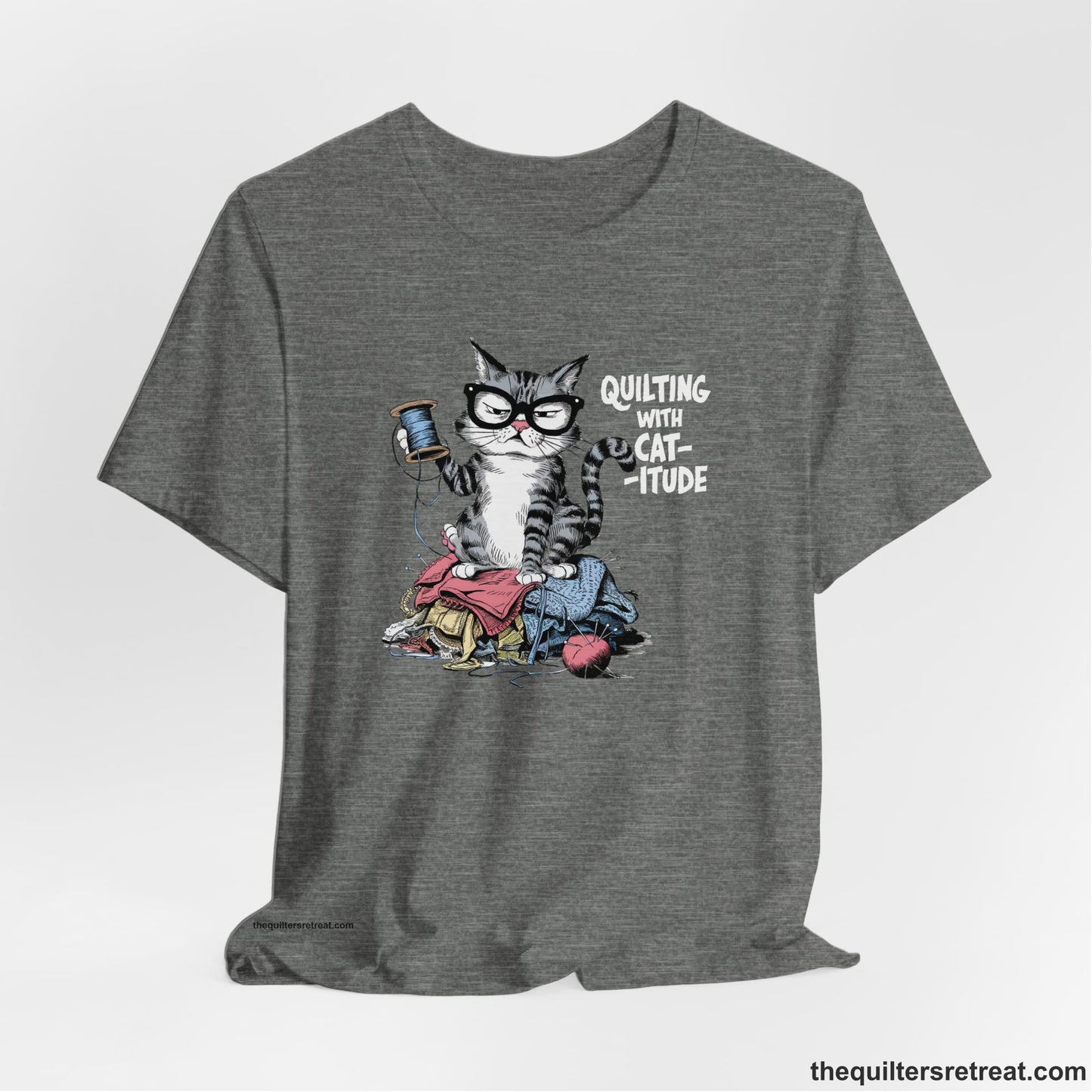 A Deep Heather Short Sleeve T-Shirt with a grumpy cat holding thread spool atop fabric pile with "Quilting with Cat-itude" text