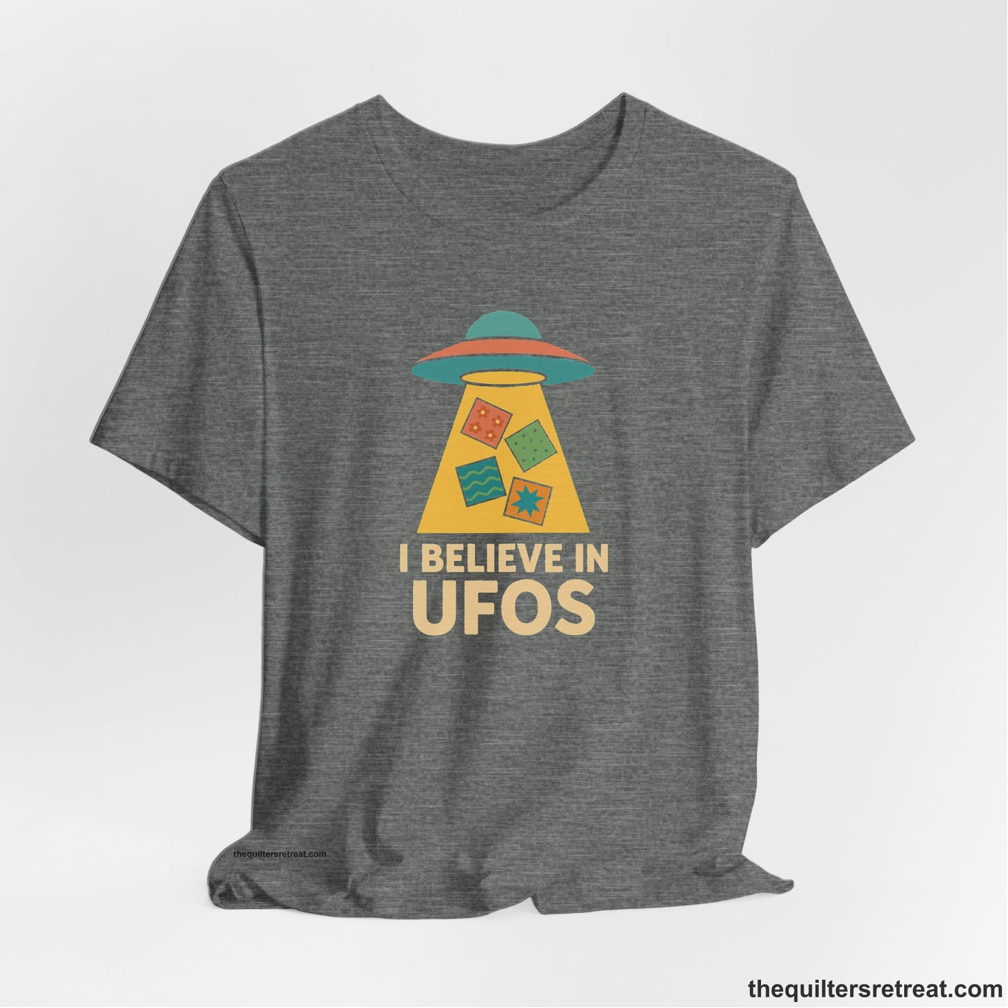 A Deep Heather Short Sleeve T-Shirt with a colorful UFO with quilt patterns and bold "I Believe in UFOs" text in retro style