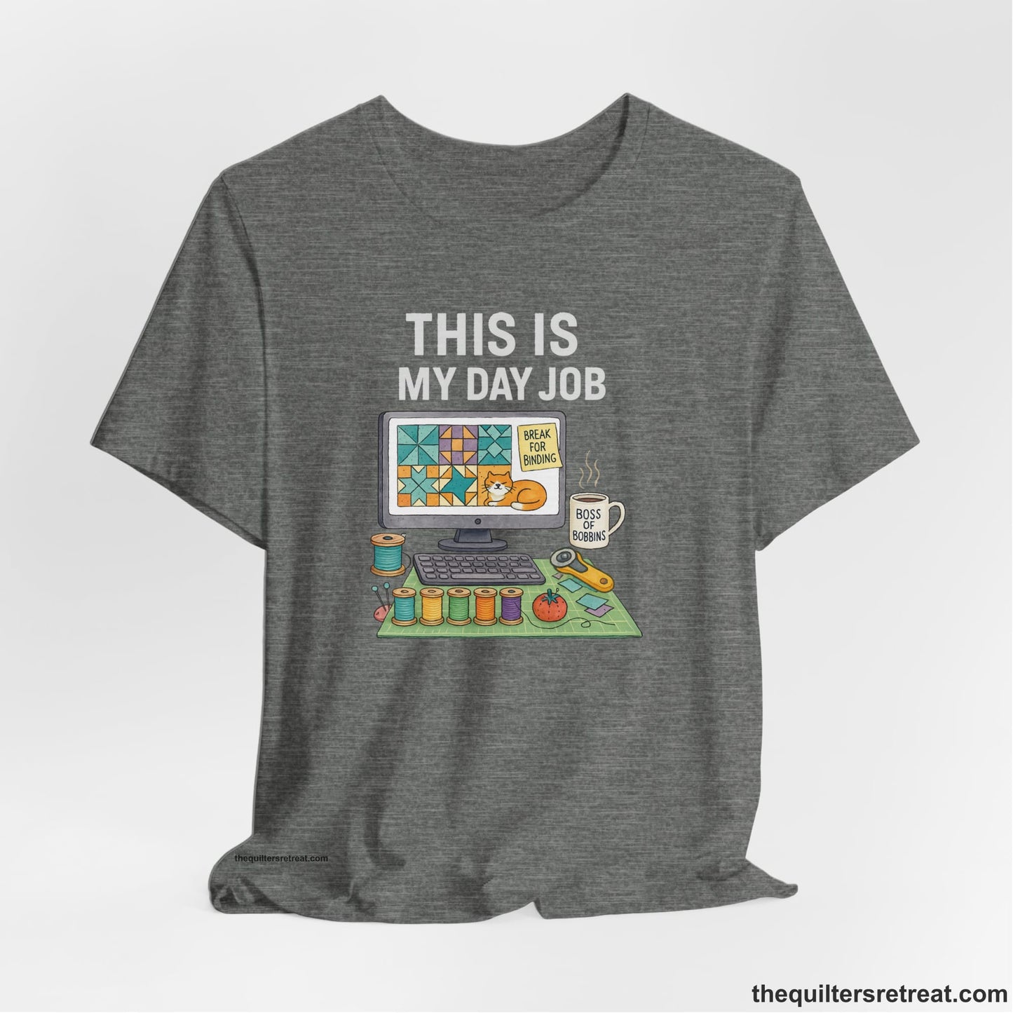 A Deep Heather Short Sleeve T-Shirt with a computer quilt design, cat illustration, "THIS IS MY DAY JOB" text with sewing tools, playful style