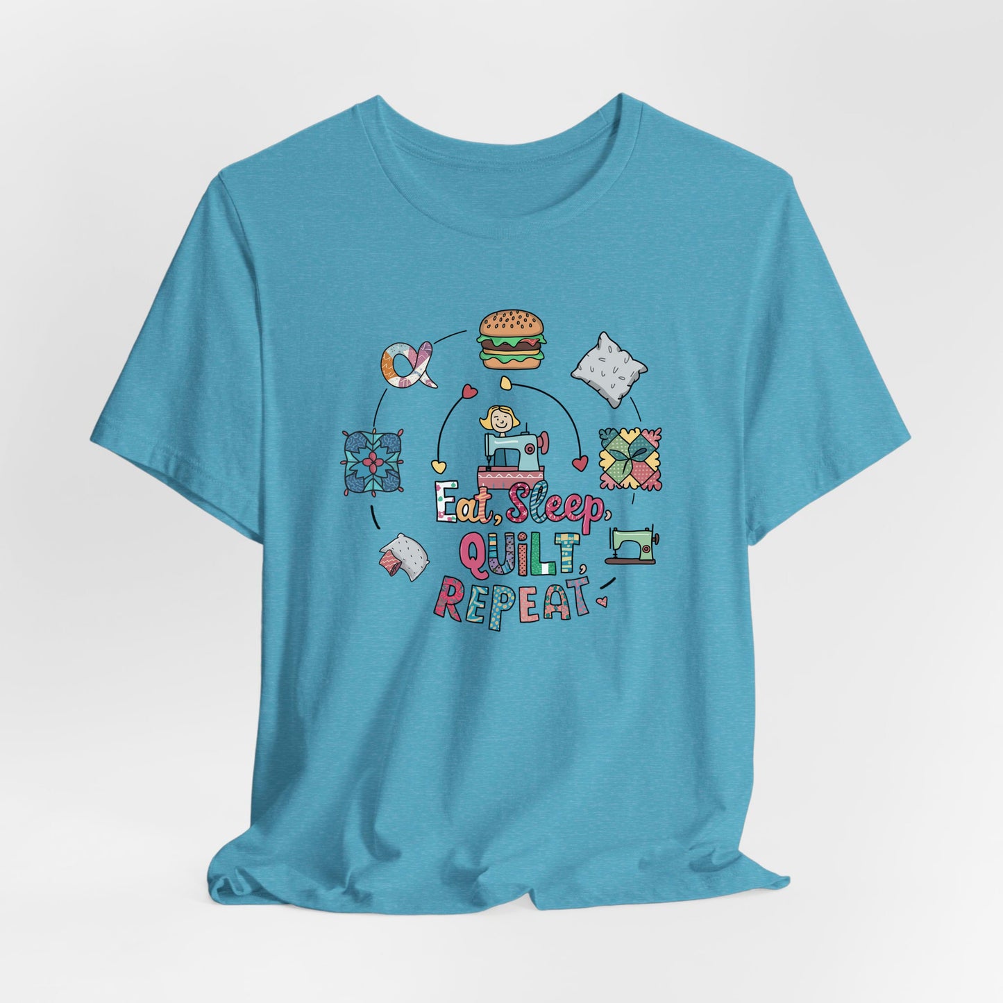 A Heather Aqua Short Sleeve T-Shirt with a cute quilting elements with "Eat, Sleep, Quilt, Repeat" text in playful style