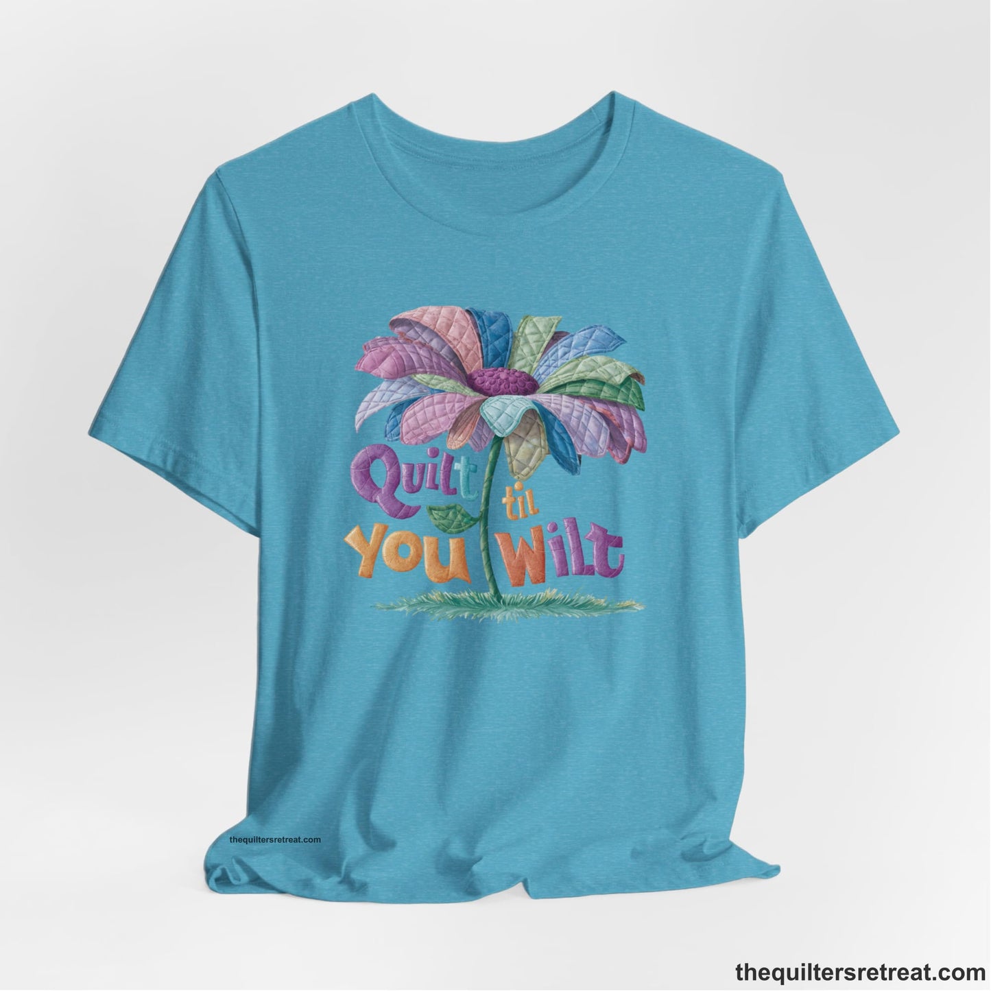 A Heather Aqua Short Sleeve T-Shirt with a whimsical quilted flower with bold "Quilt til You Wilt" text