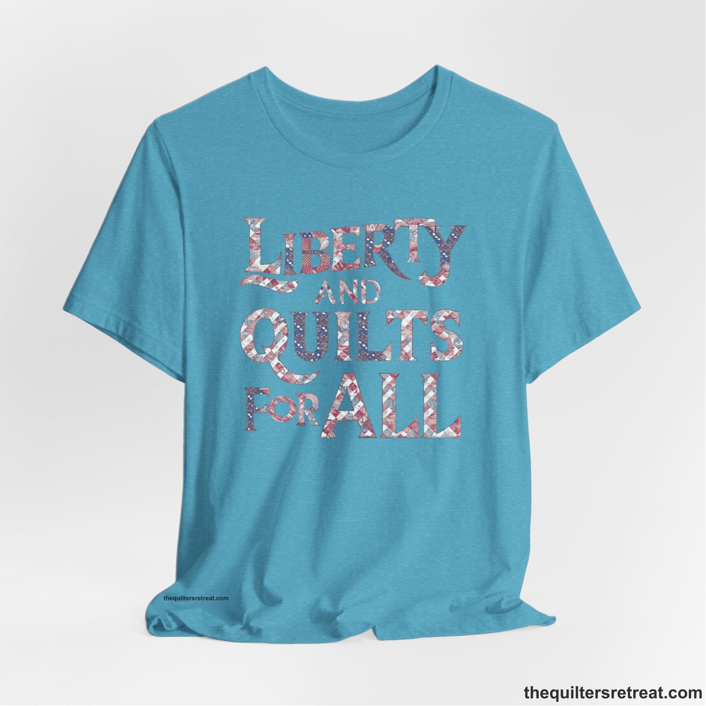 A Heather Aqua Short Sleeve T-Shirt with a Liberty and Quilts for All" text with patchwork quilt pattern in a vintage style