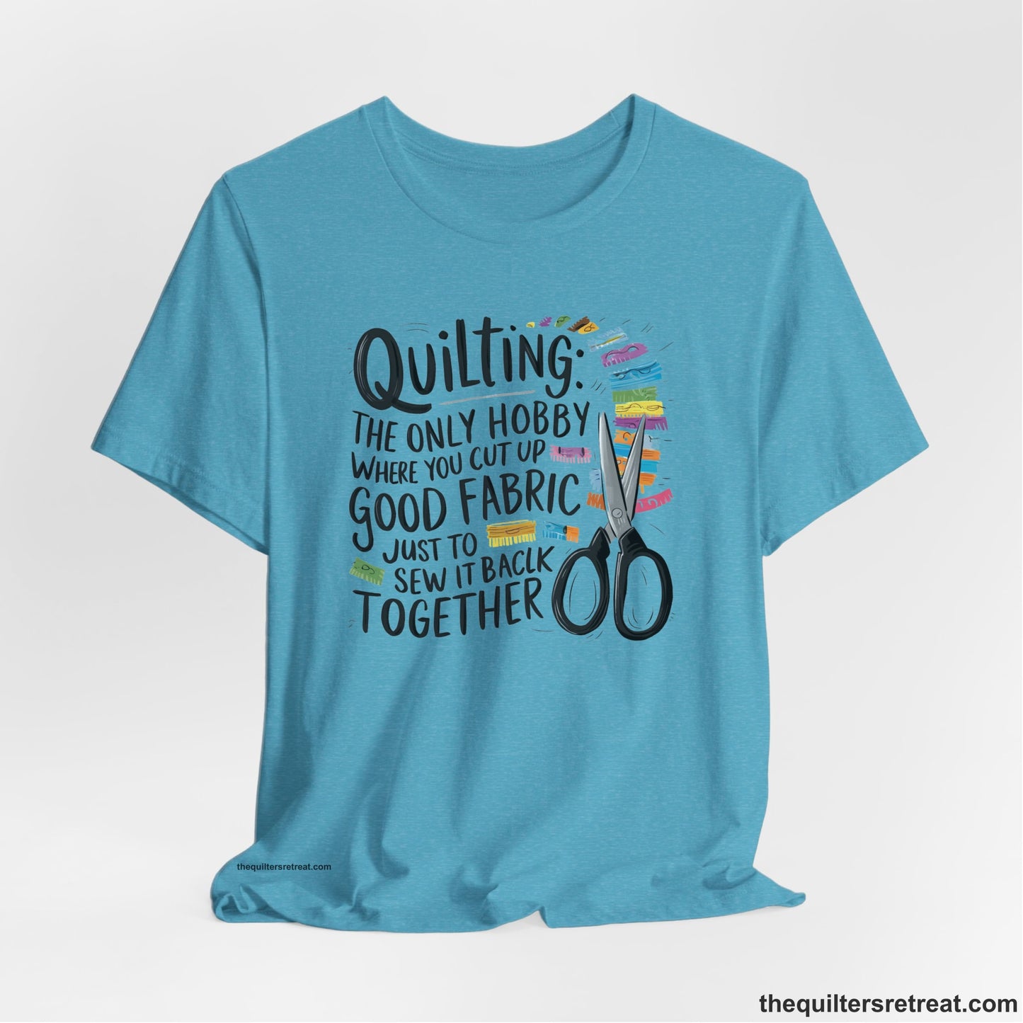 A Heather Aqua Short Sleeve T-Shirt with a quilting-themed text with colorful fabric pieces and scissors in a whimsical style