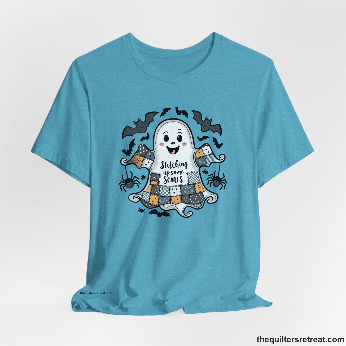 A Heather Aqua Short Sleeve T-Shirt with a cute patchwork ghost with "Stitching up some Scares" text and playful bats in a whimsical style