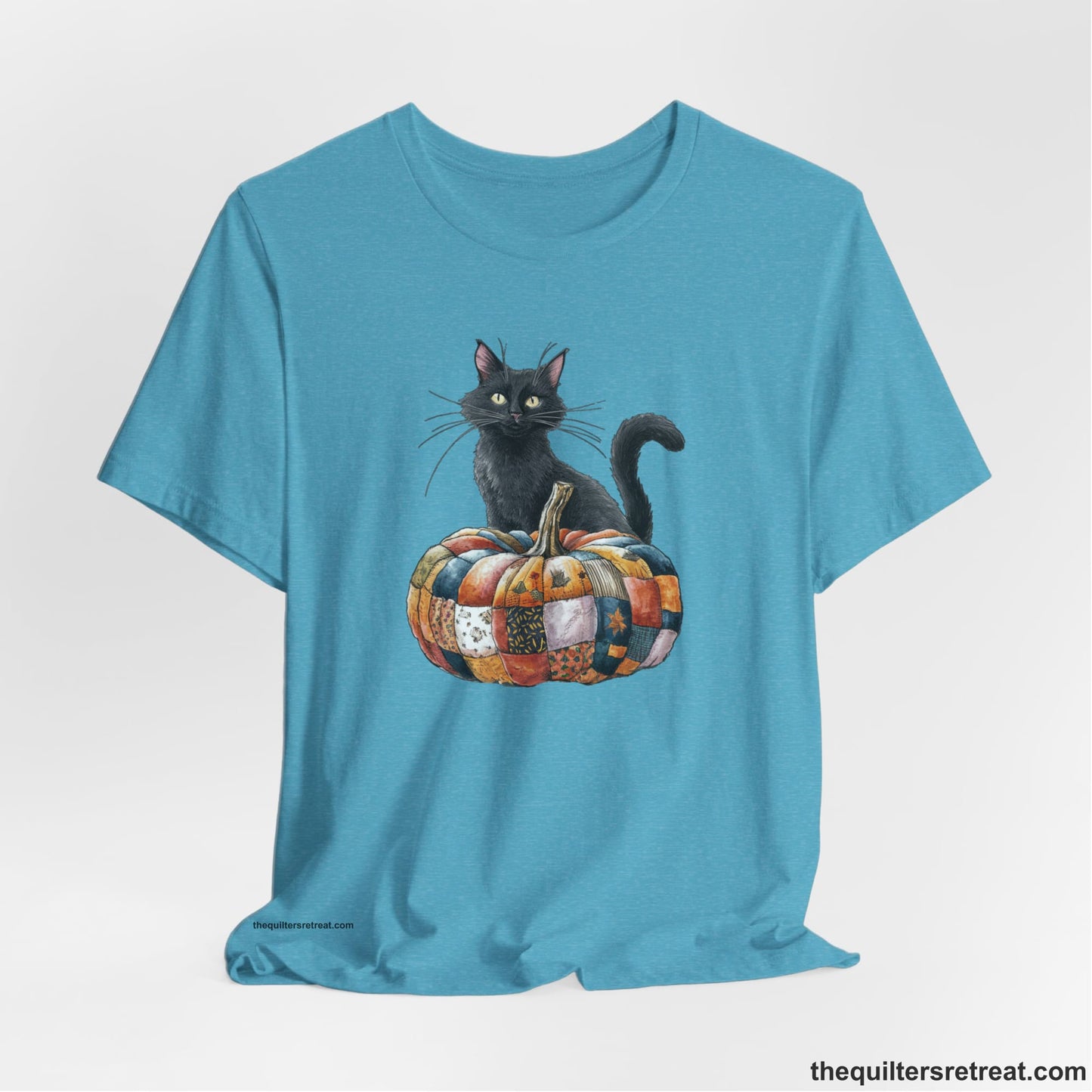 A Heather Aqua Short Sleeve T-Shirt with a black cat with a quilted patchwork pumpkin in a whimsical autumn style