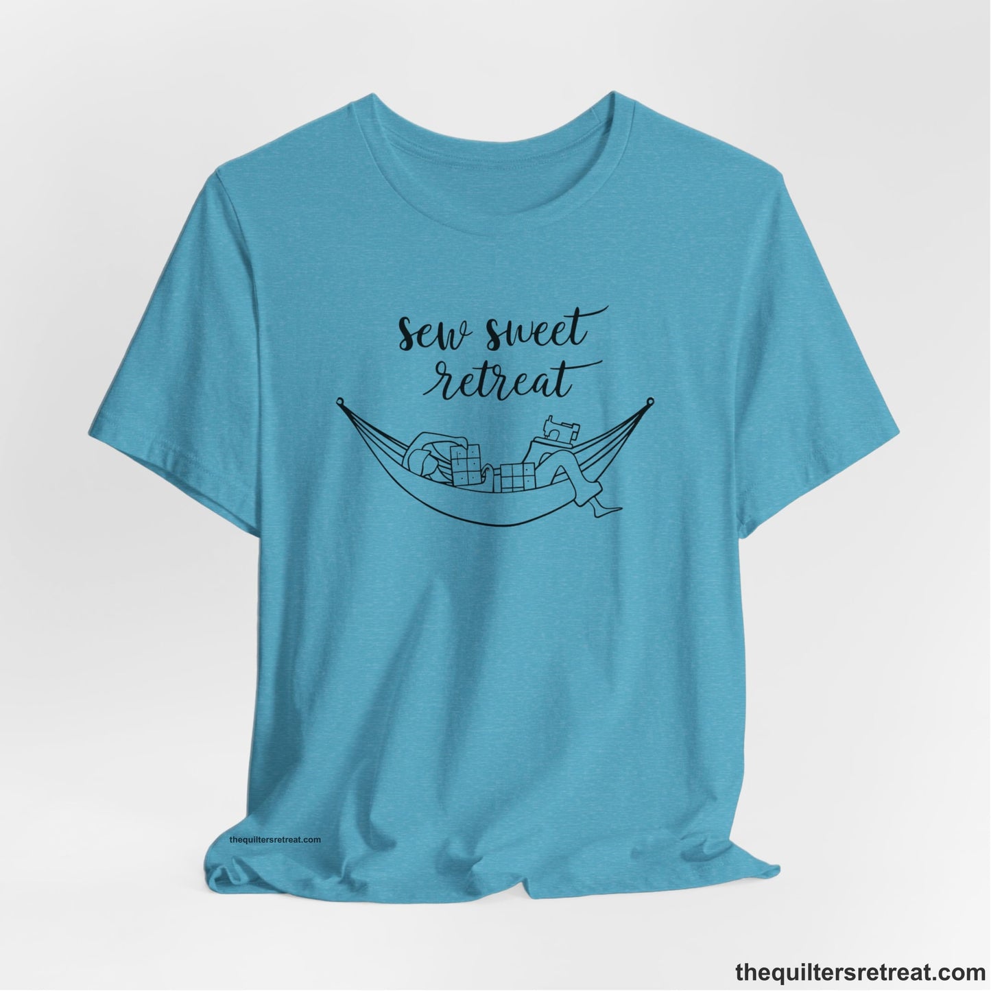 A Heather Aqua Short Sleeve T-Shirt with a sewing machine and thread spools with "Sew Sweet Retreat" in whimsical script