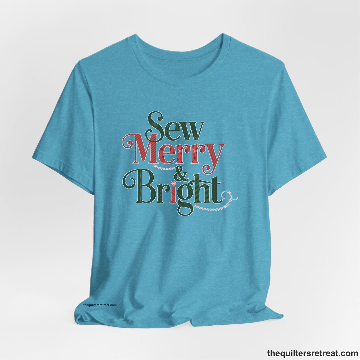 A Heather Aqua Short Sleeve T-Shirt with a festive "Sew Merry & Bright" text with decorative holiday patterns