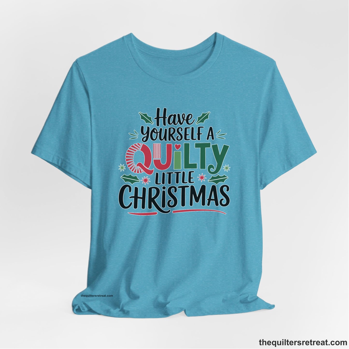 A Heather Aqua Short Sleeve T-Shirt with a festive "Have Yourself a Quilty Little Christmas" text with holly and quilt patterns